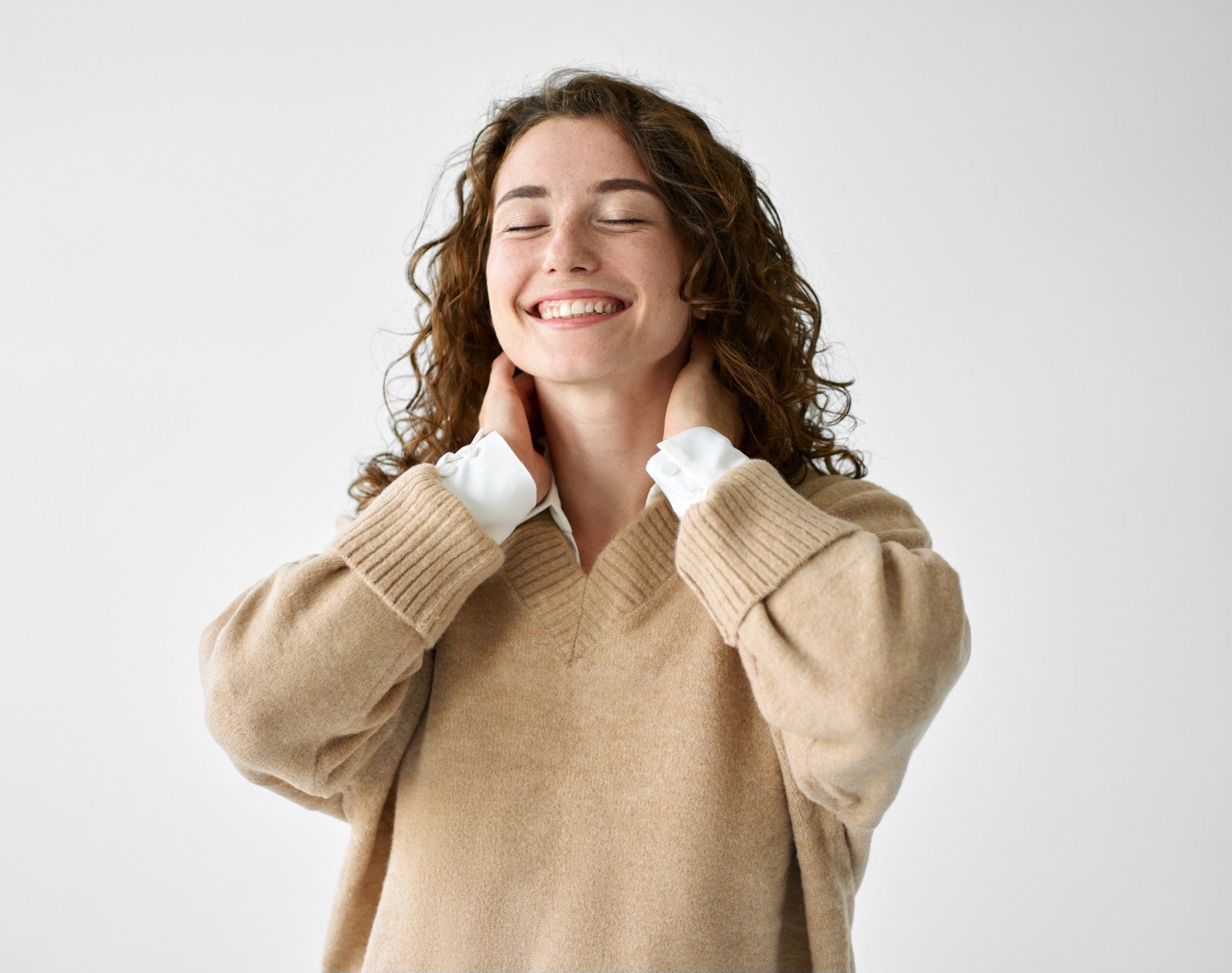 Smiling woman touching her neck, expressing relief from neck tension and discomfort, showcasing improved well-being and comfort.