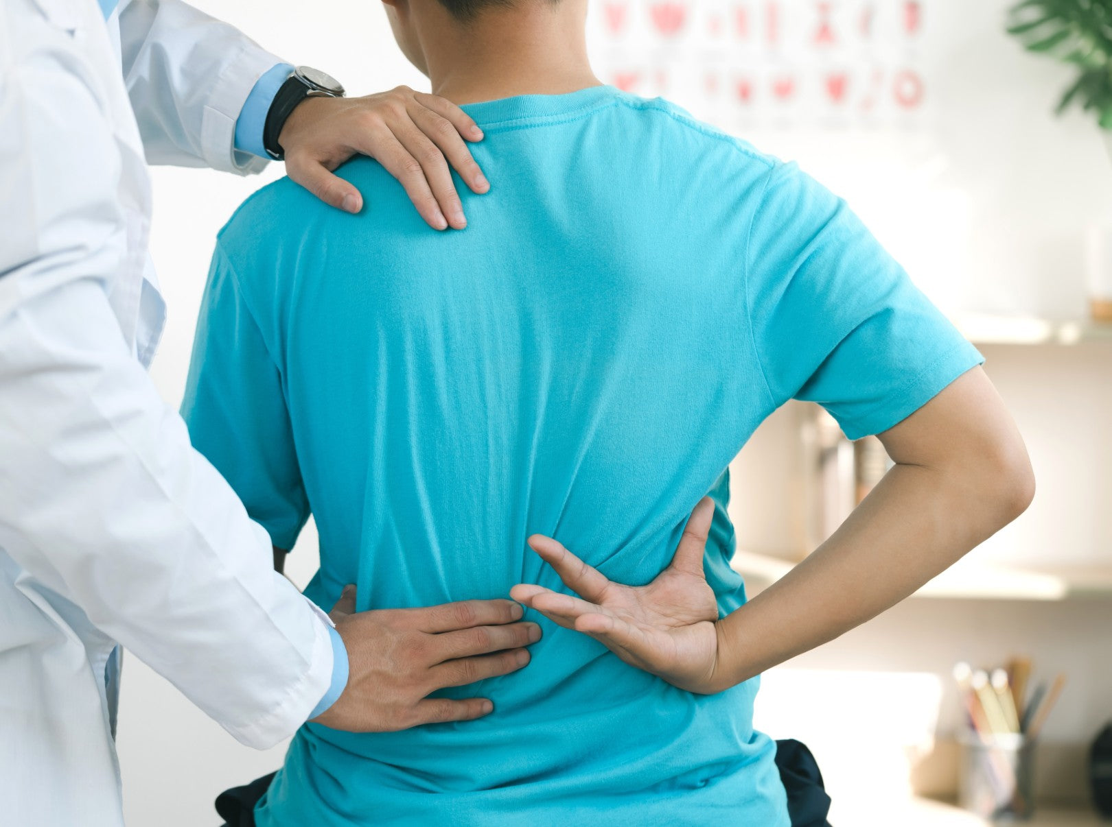 Doctor examining a patient's back, focusing on identifying areas of pain and discomfort related to posture or spinal issues.