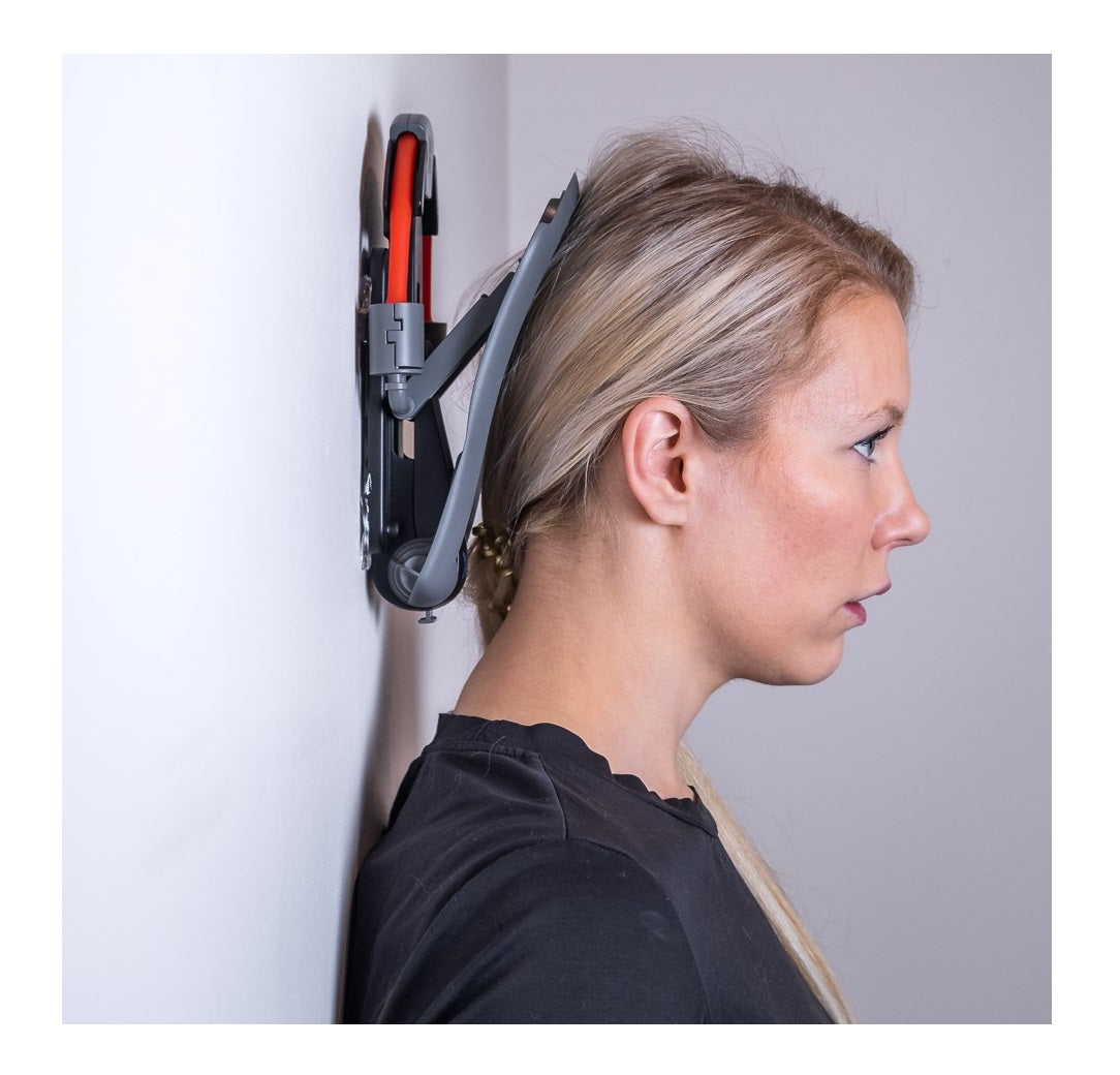 Woman demonstrating proper use of the XtreemNek neck strengthening device against a wall, performing the Chin Tuck Exercise for improved posture and neck pain relief.