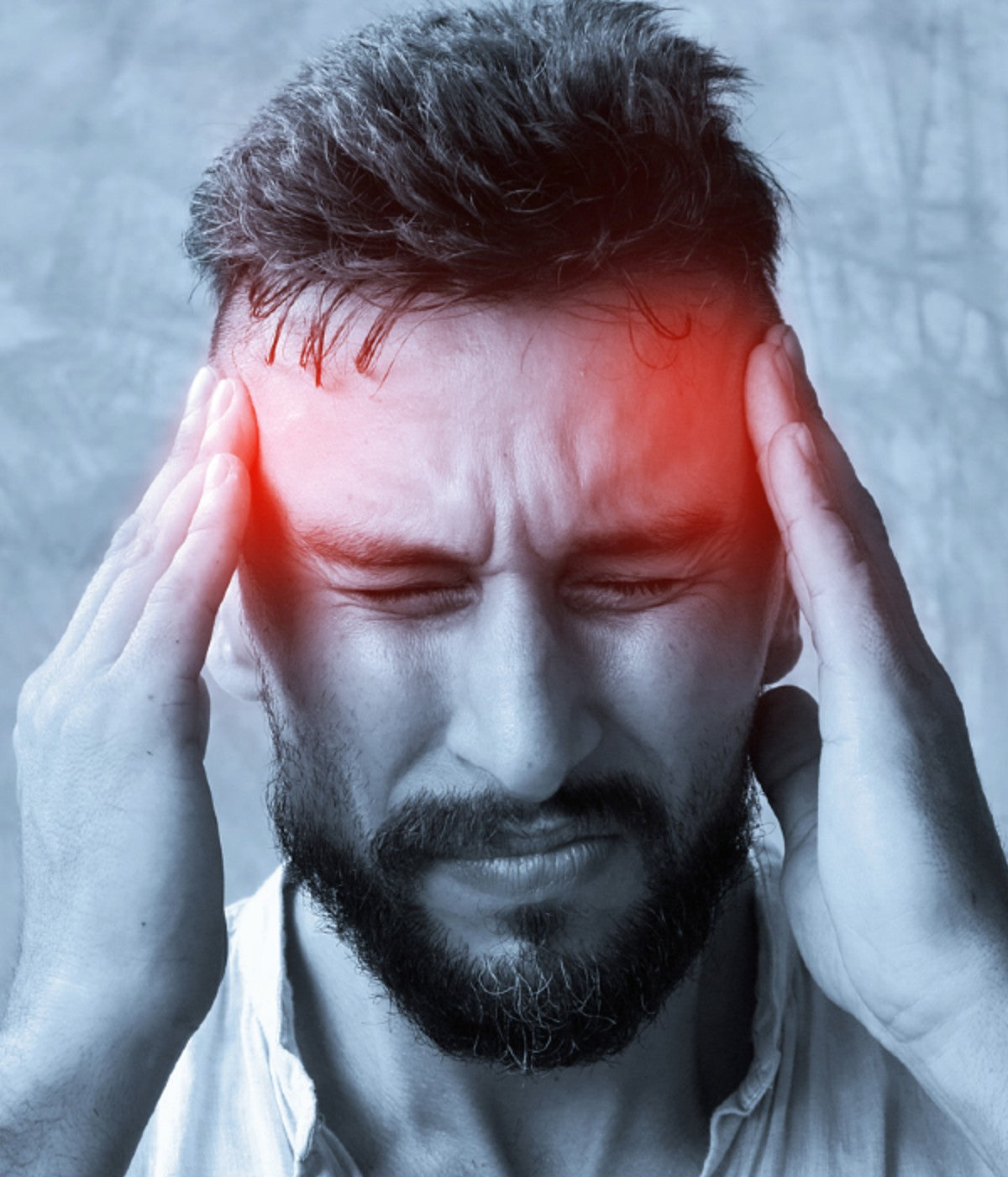 Man experiencing a headache, holding his temples with visible red pain points, illustrating the effects of neck strain and tension headaches.